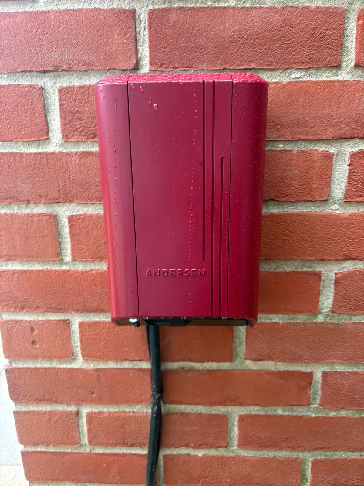 Andersen A2 EV charger in a deep red finish, installed on a brick wall