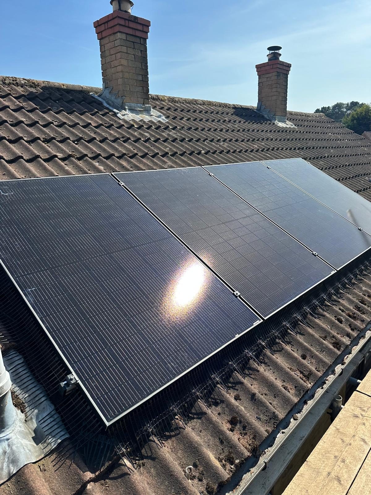 Close-up of a black solar panel array on a Dorset roof, in bright sunlight